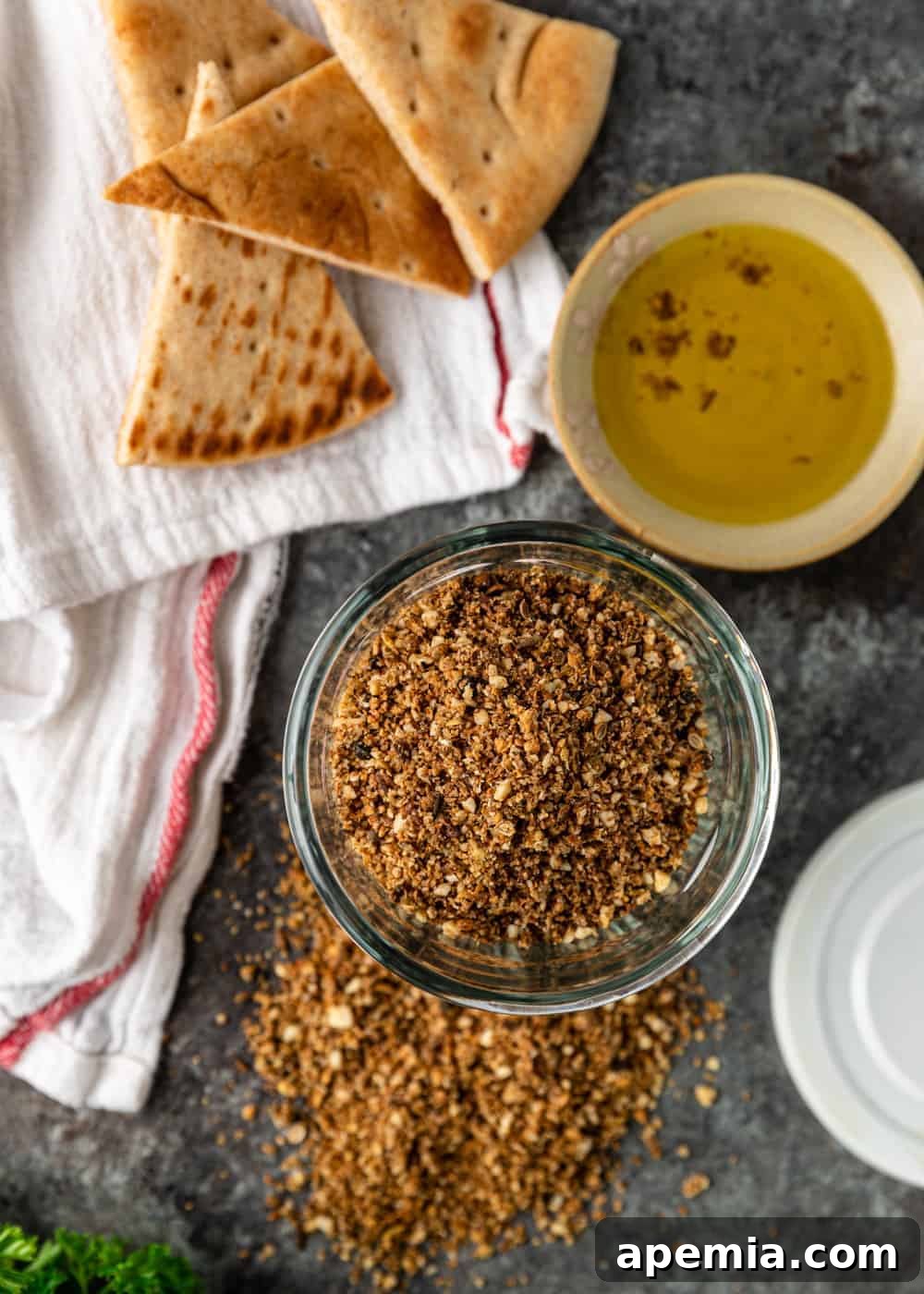 Overhead image: A beautiful bowl of homemade Egyptian dukkah, freshly ground from toasted almonds, seeds, and spices, served alongside warm pita bread and a dipping sauce.