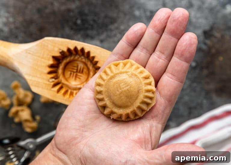 The delicate process of removing a shaped cookie dough from its maamoul cookie mold, revealing the detailed design.
