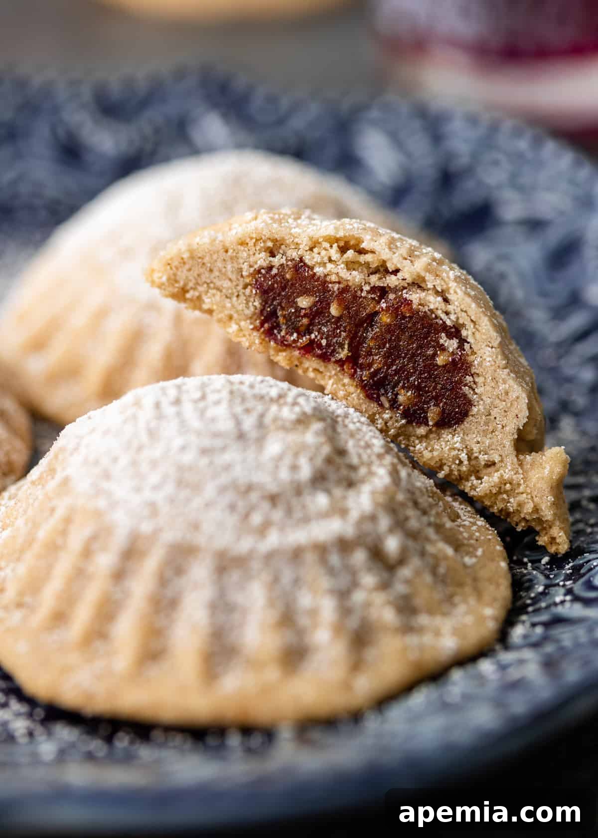 A beautiful closeup of a plate filled with maamoul cookies, prominently featuring their rich date filling and intricate patterns.