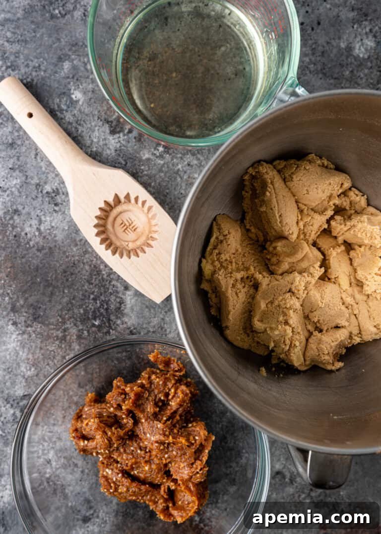 Overhead view of maamoul cookie dough in a stand mixer bowl, positioned next to a separate bowl containing the rich date paste filling, showcasing the two main components.