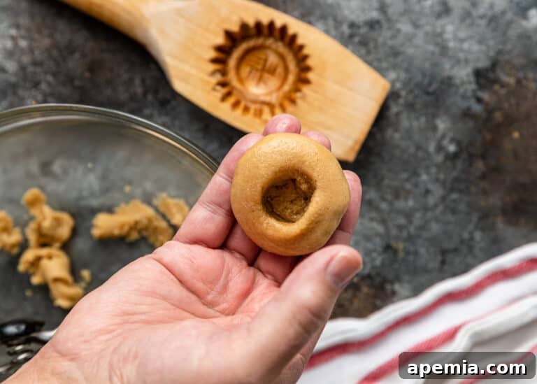 Raw cookie dough with a created hole in the center, held in the palm of a hand, ready for filling.