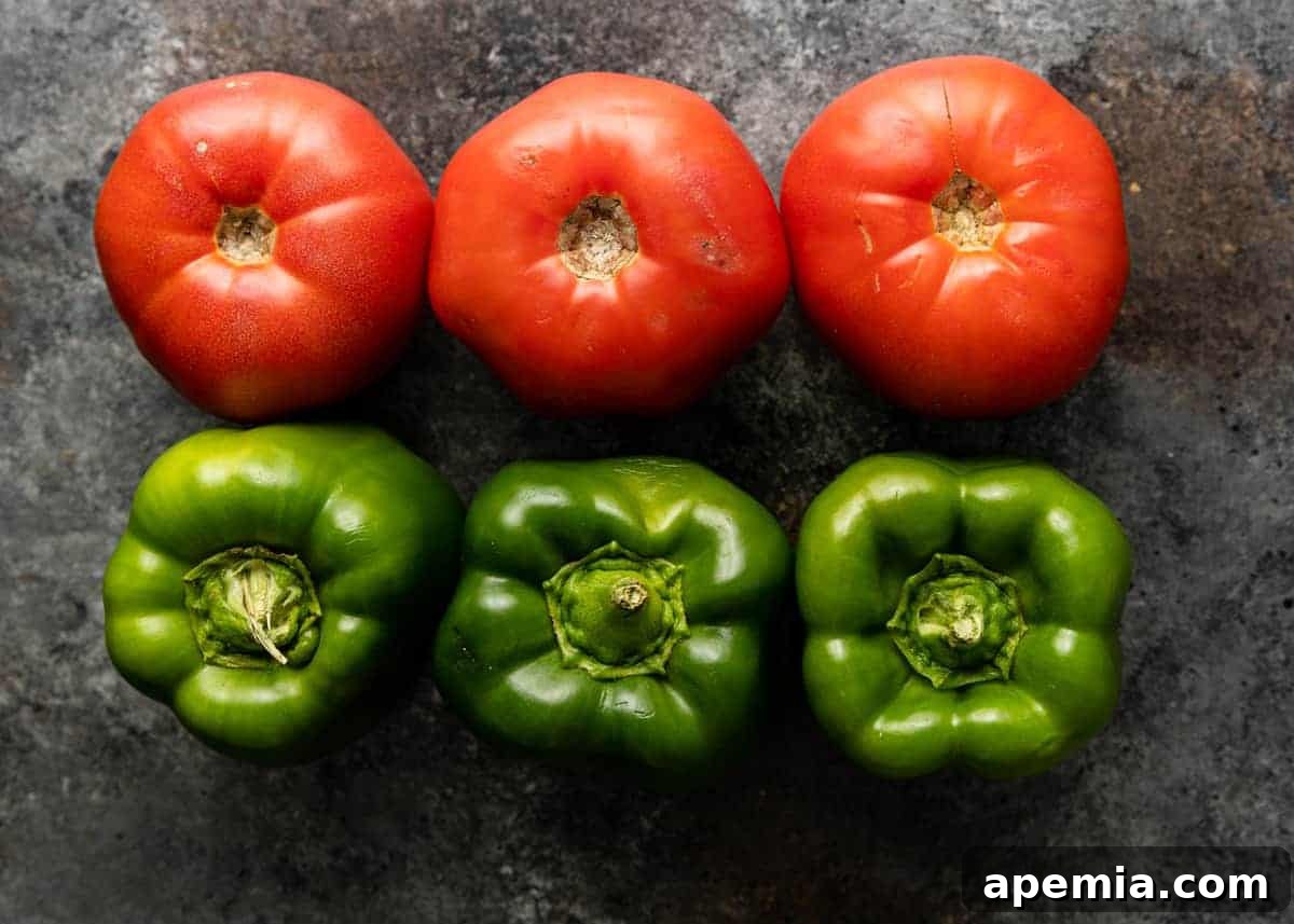 Overhead view of 3 fresh red tomatoes and 3 bell peppers on a gray background