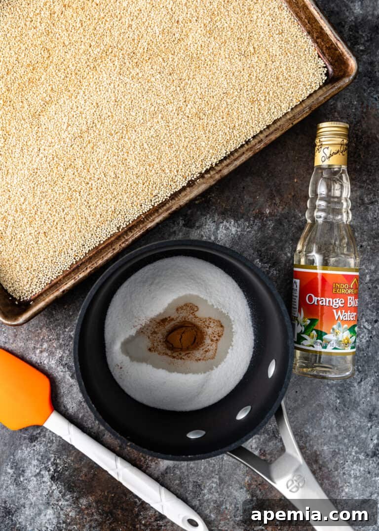 overhead: white seeds on baking sheet, bottled orange blossom water, sugar in saucepan