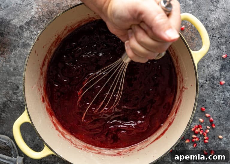 Whisking pomegranate syrup in a large pot until fully incorporated for the Lokum recipe.