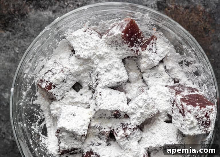 Lokum candies being tossed in powdered sugar and cornstarch for a final coating.