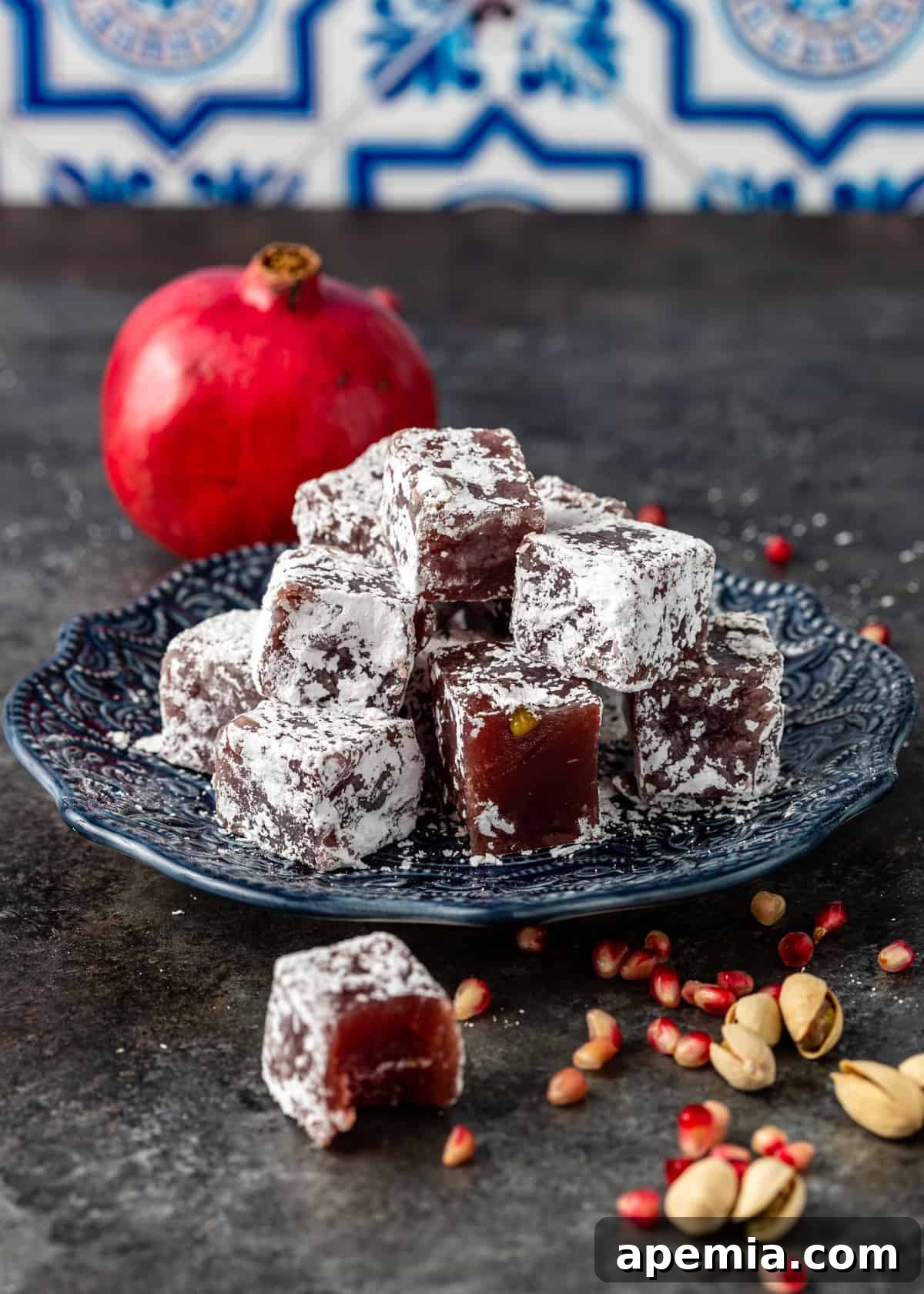 Side view of vibrant pomegranate and pistachio gelatin candy on a plate, showcasing its texture.
