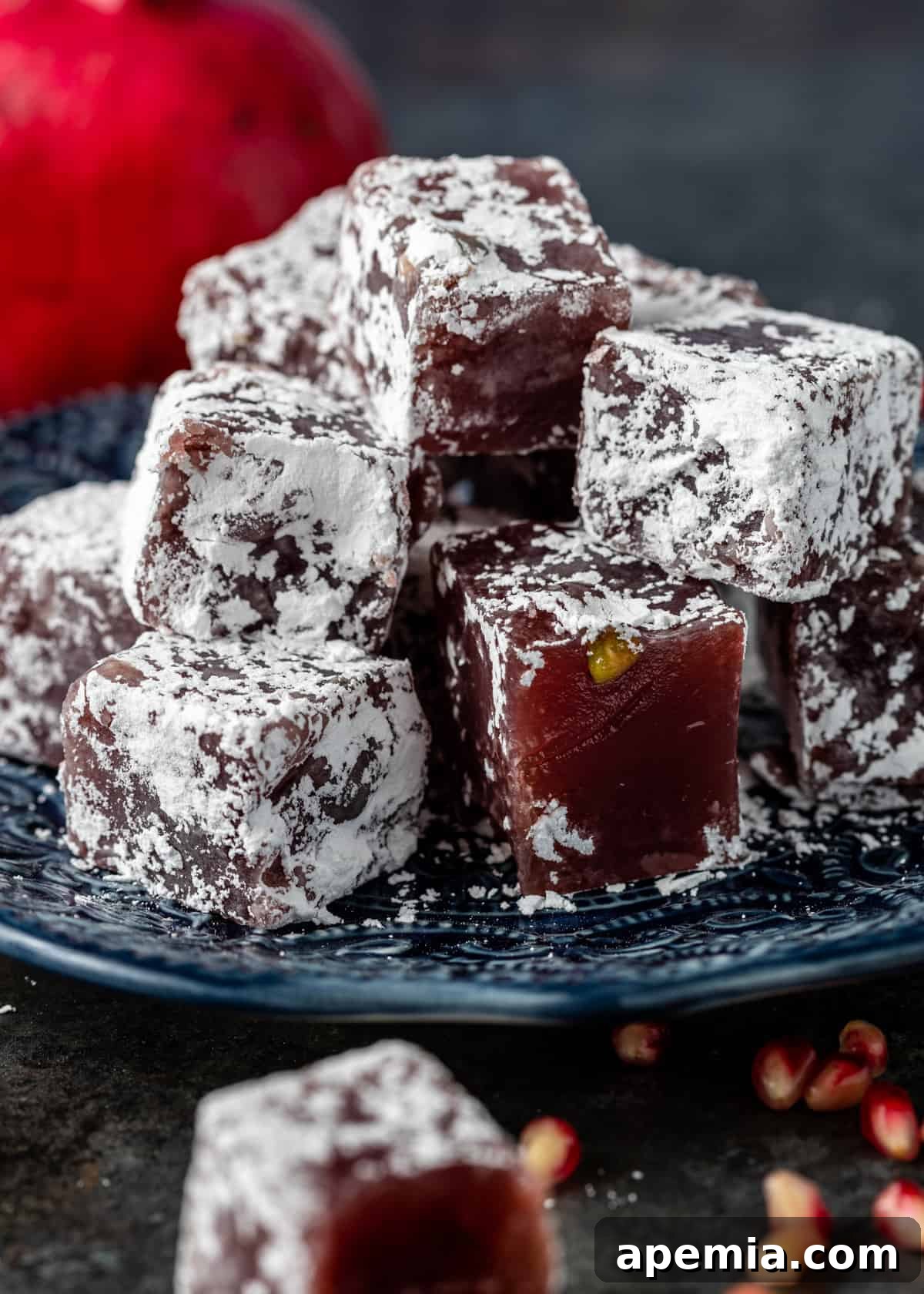 Closeup of perfectly cut cubes of pomegranate pistachio Turkish Delight candy on a blue plate.