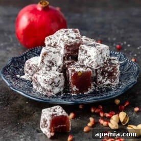 Homemade Turkish Delight (Lokum) on a blue plate with pomegranates, ready to serve.