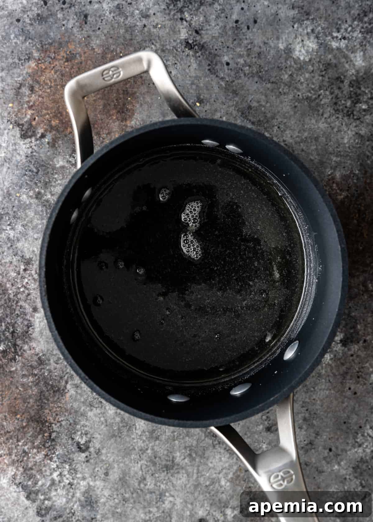 The cooked sugar syrup in a saucepan, having reached the soft ball stage at 240°F.