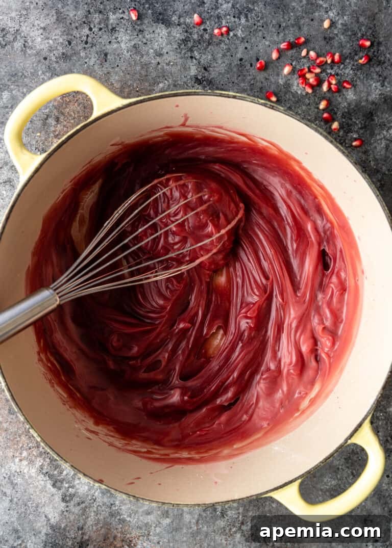The fully cooked and thickened pomegranate base in a large pot, ready for the syrup.