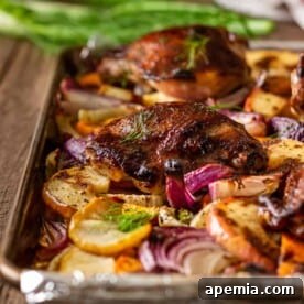 crispy roasted chicken thighs on baking sheet with slices of fennel, sweet potatoes and red apple