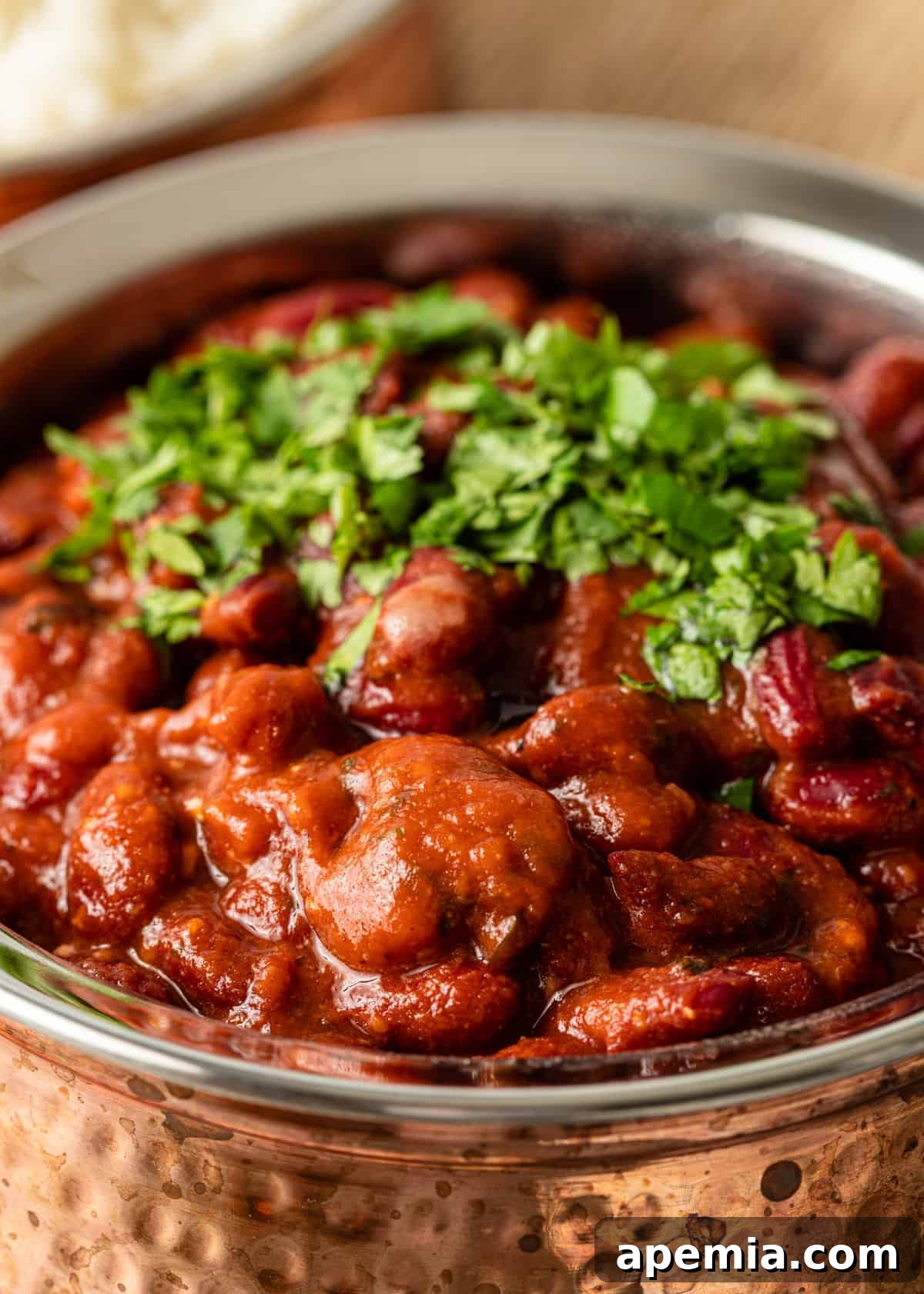 Closeup shot of Rajma Chawal in a bowl, richly garnished with freshly chopped cilantro, showcasing the texture and vibrant colors of the curry.