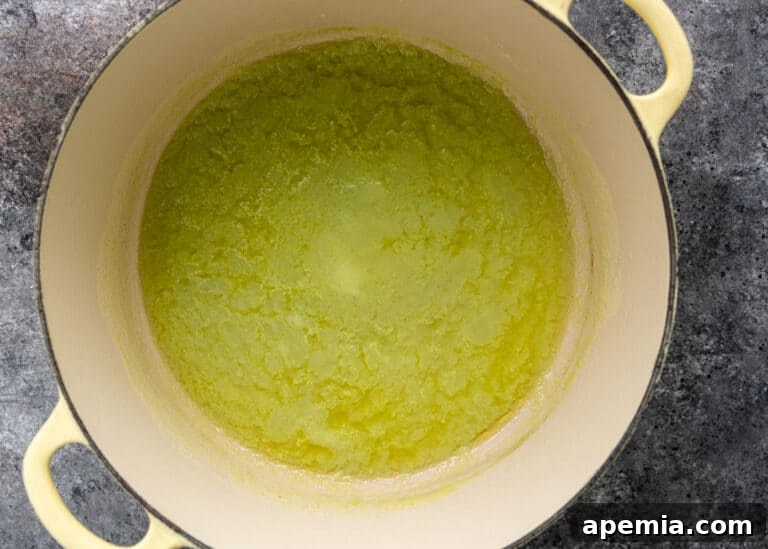 Overhead view of the onion and chili paste being cooked in melted ghee in a Dutch oven.