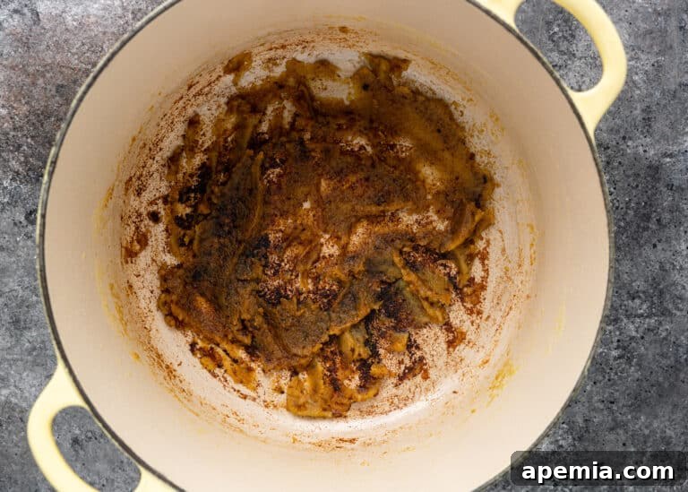 Overhead view of the onion and chili paste after 18 minutes of simmering in a Dutch oven, now reduced, thickened, and a dark golden brown color.