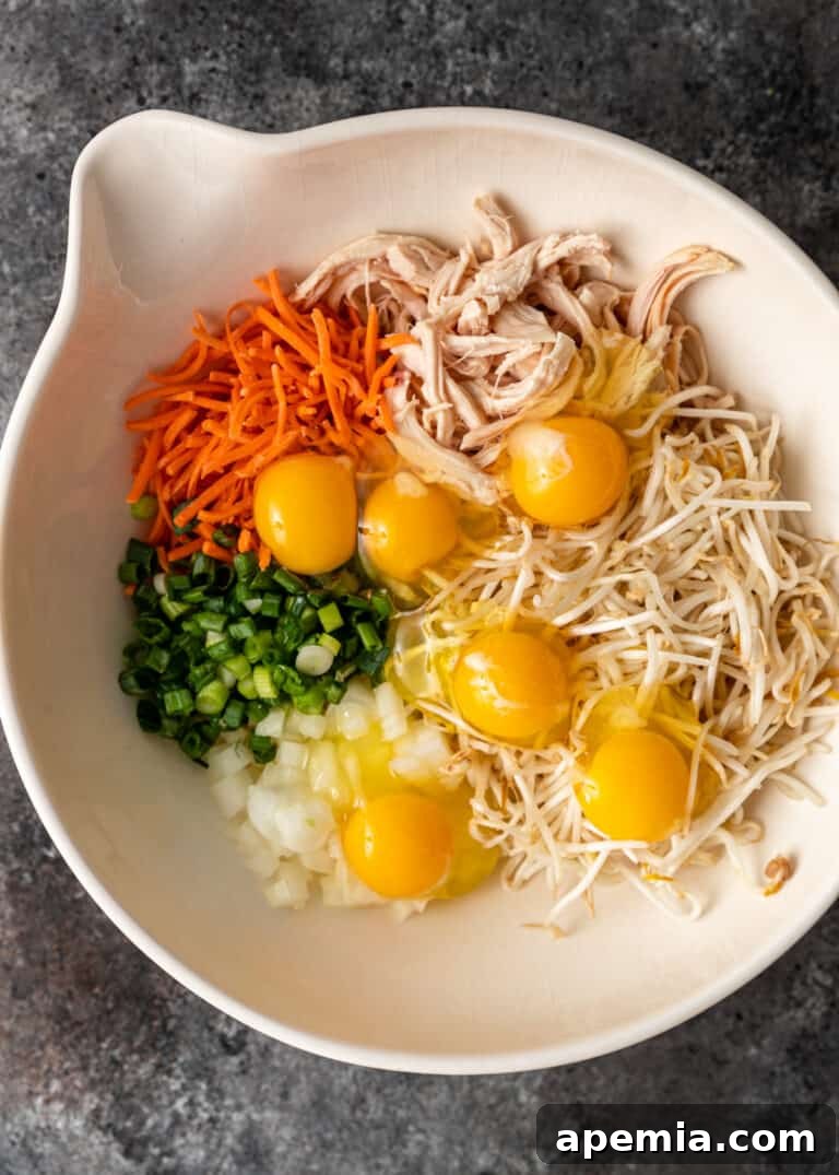overhead process shot: eggs added to shredded chicken, carrot, scallion and bean threads