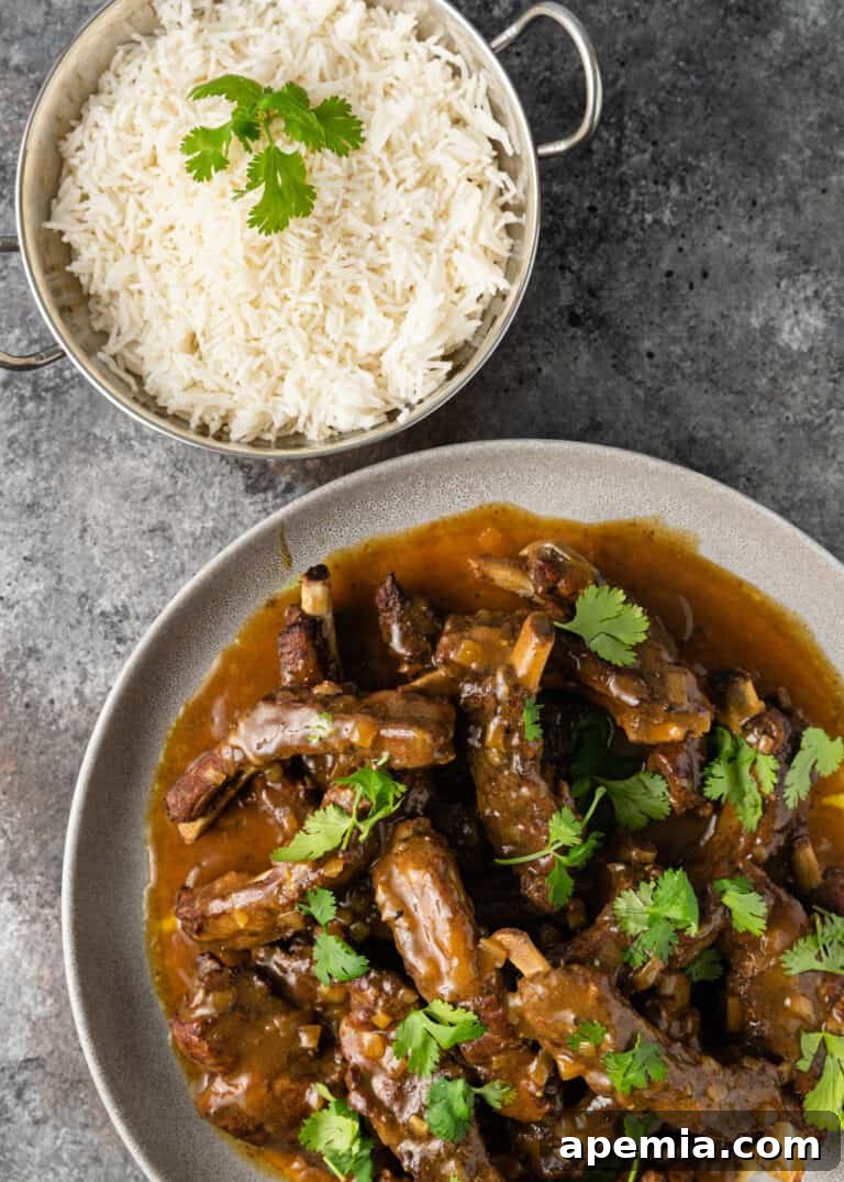 Plated Instant Pot Asian pork ribs with rich brown curry sauce next to a bowl of fluffy basmati rice, garnished with fresh cilantro