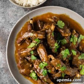 Overhead photo: curried pork ribs covered in rich curry sauce on white dinner plate