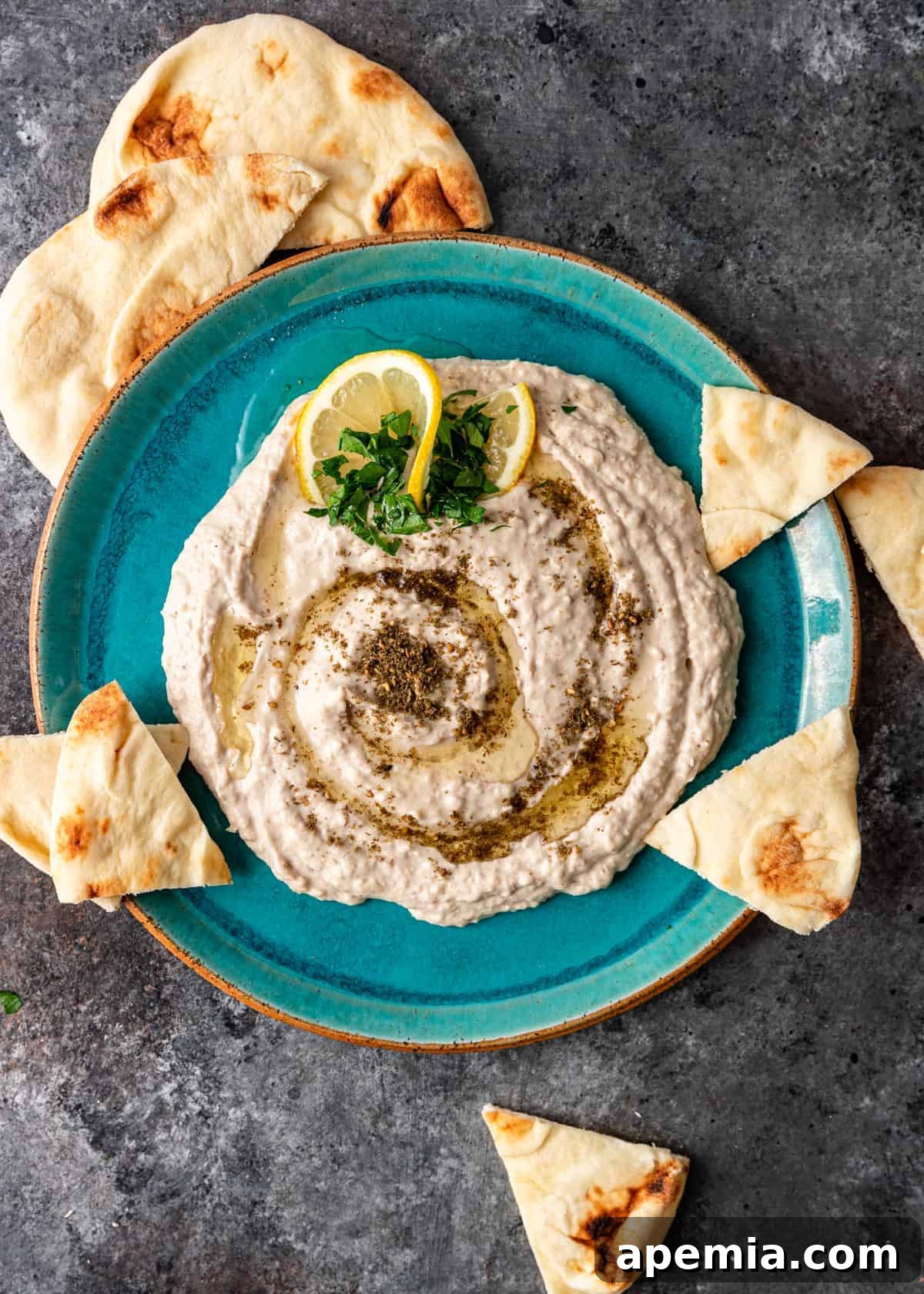 overhead: white bean hummus on blue plate with pita bread triangles