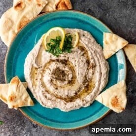 overhead: white bean hummus seasoned with zaatar on aqua blue plate with pita chips