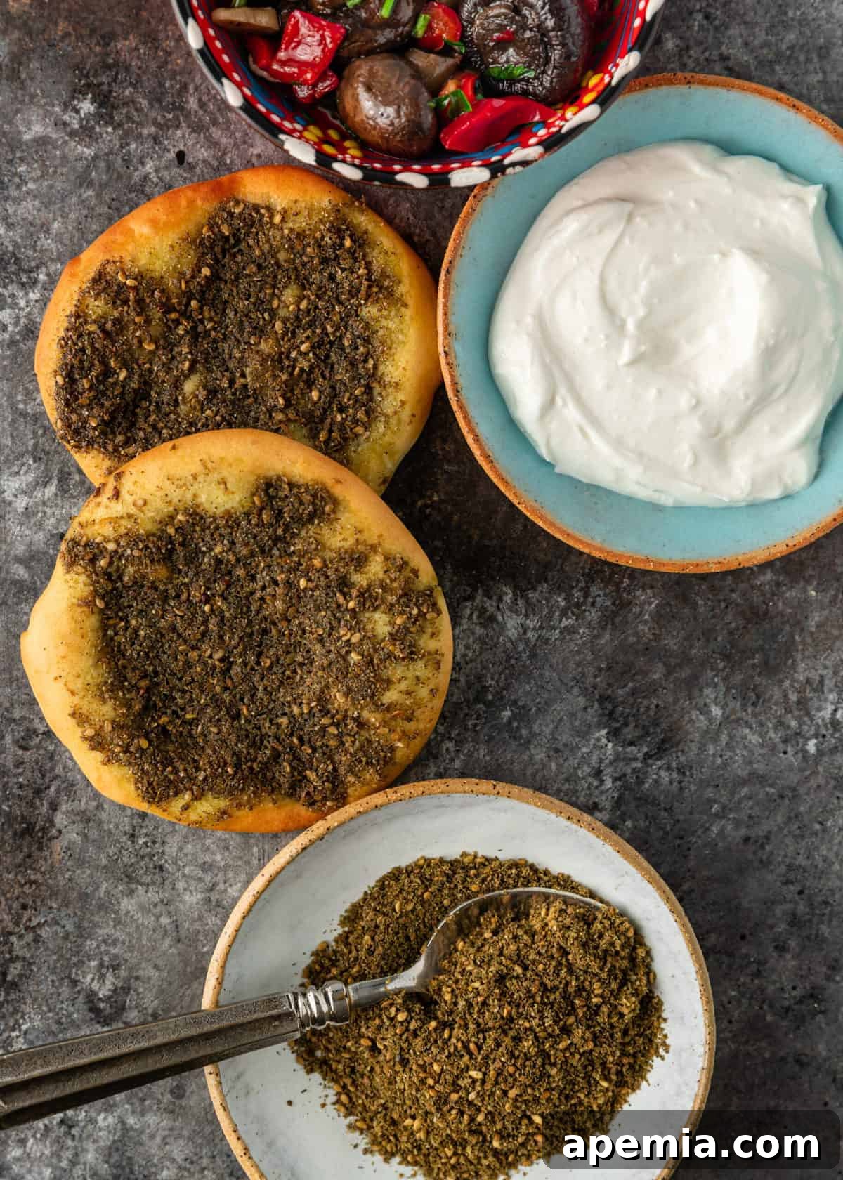 Crafting Your Own Lebanese Zaatar Blend 4 A close-up overhead shot of Manakeesh, a traditional Lebanese flatbread, generously topped with Za'atar spice blend and dollops of creamy labneh, showcasing a delicious way to enjoy the blend.