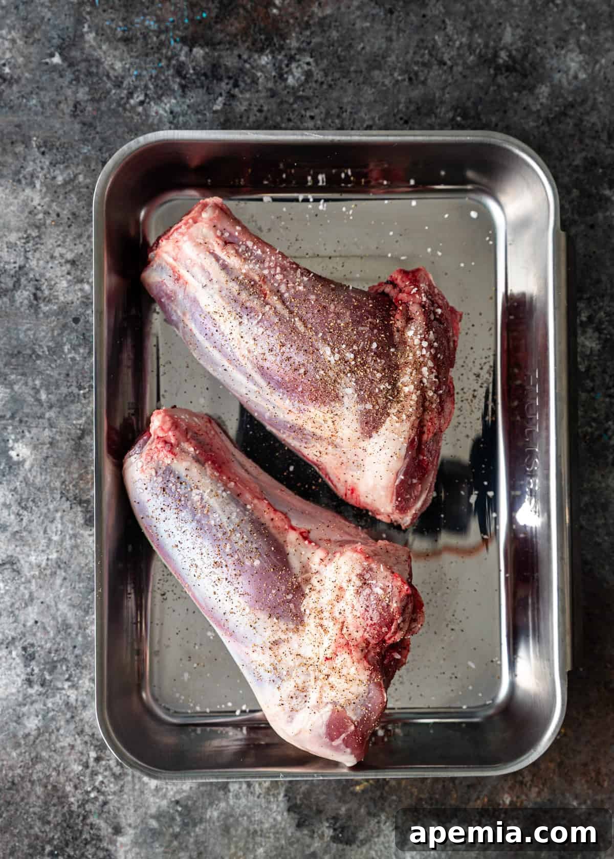 overhead process shot: seasoned lamb shanks in baking dish