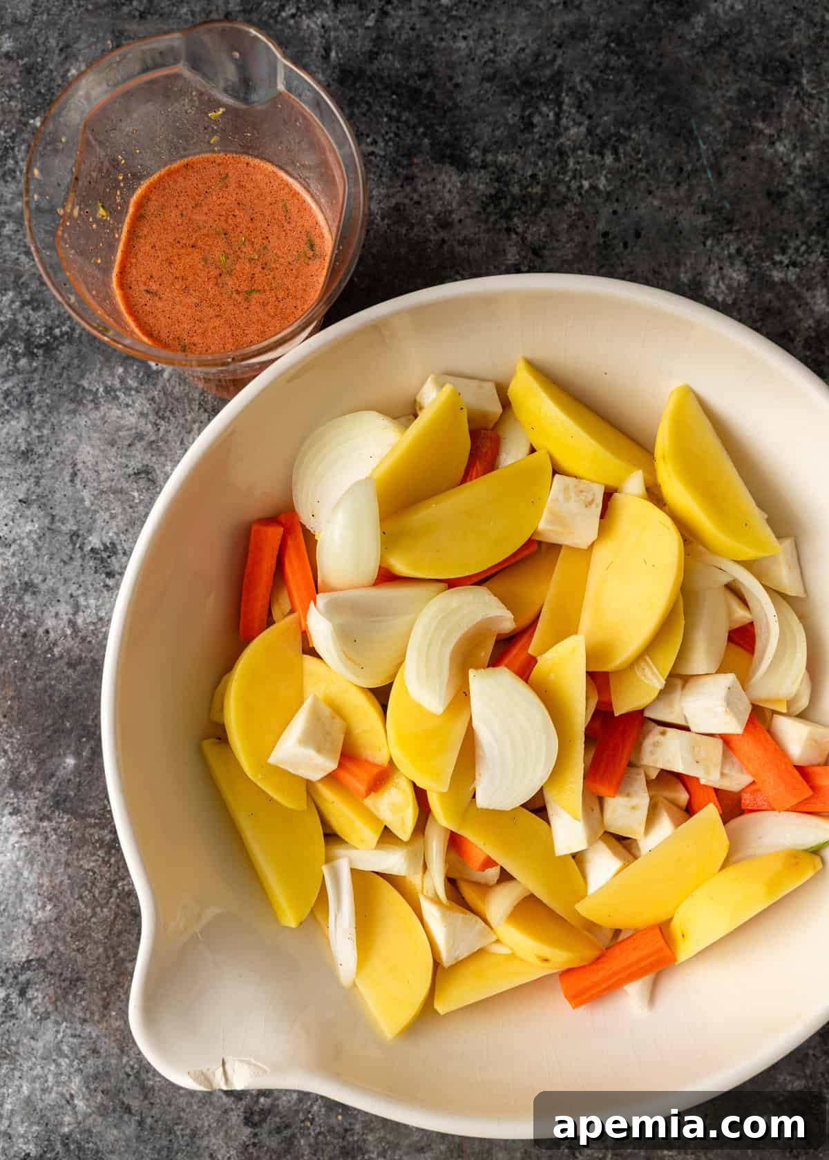overhead process shot: cut vegetables in bowl with liquid in measuring cup on side
