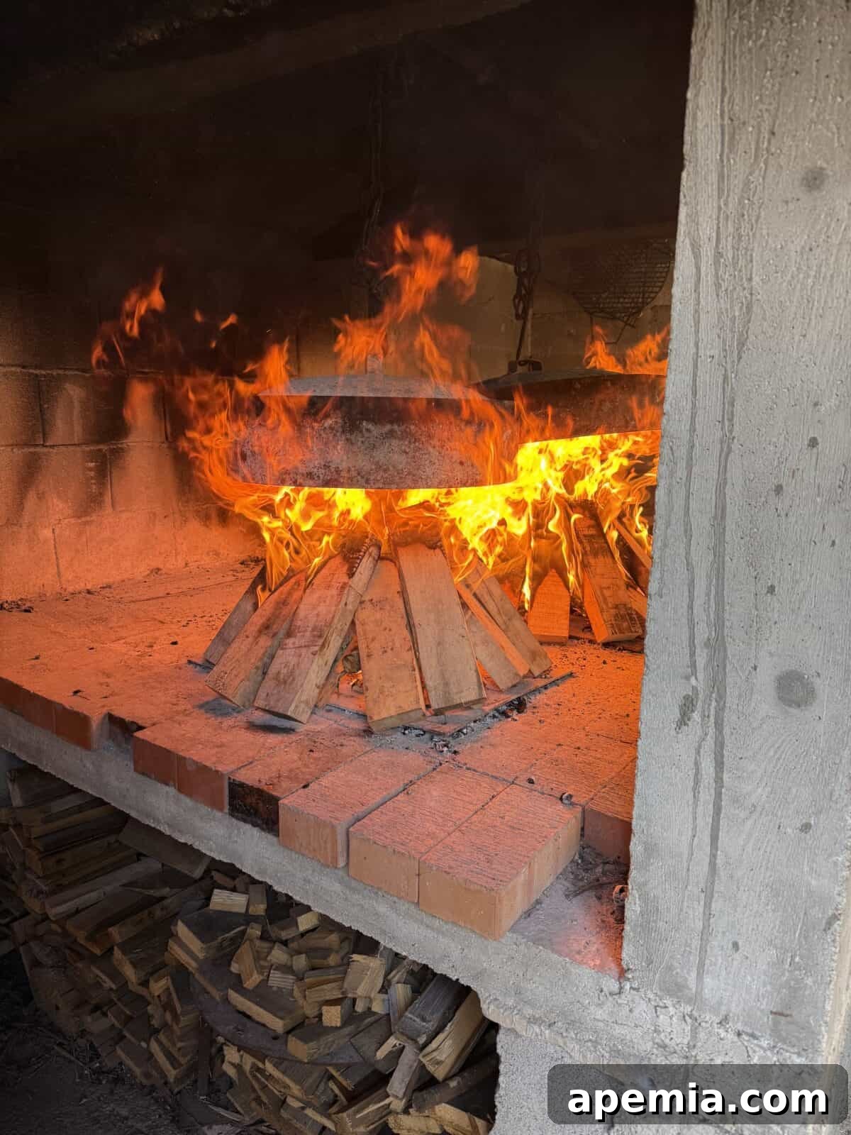 side view process shot: chopped wood in cement and brick table inside smokehouse