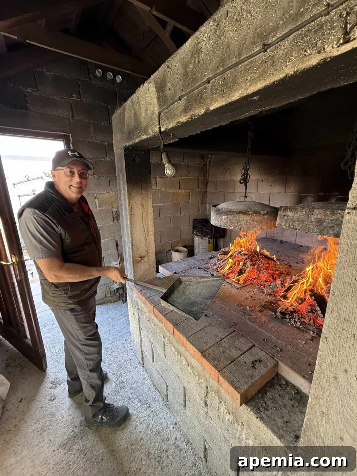 side view process shot: me standing by chopped wood in cement and brick table inside smokehouse