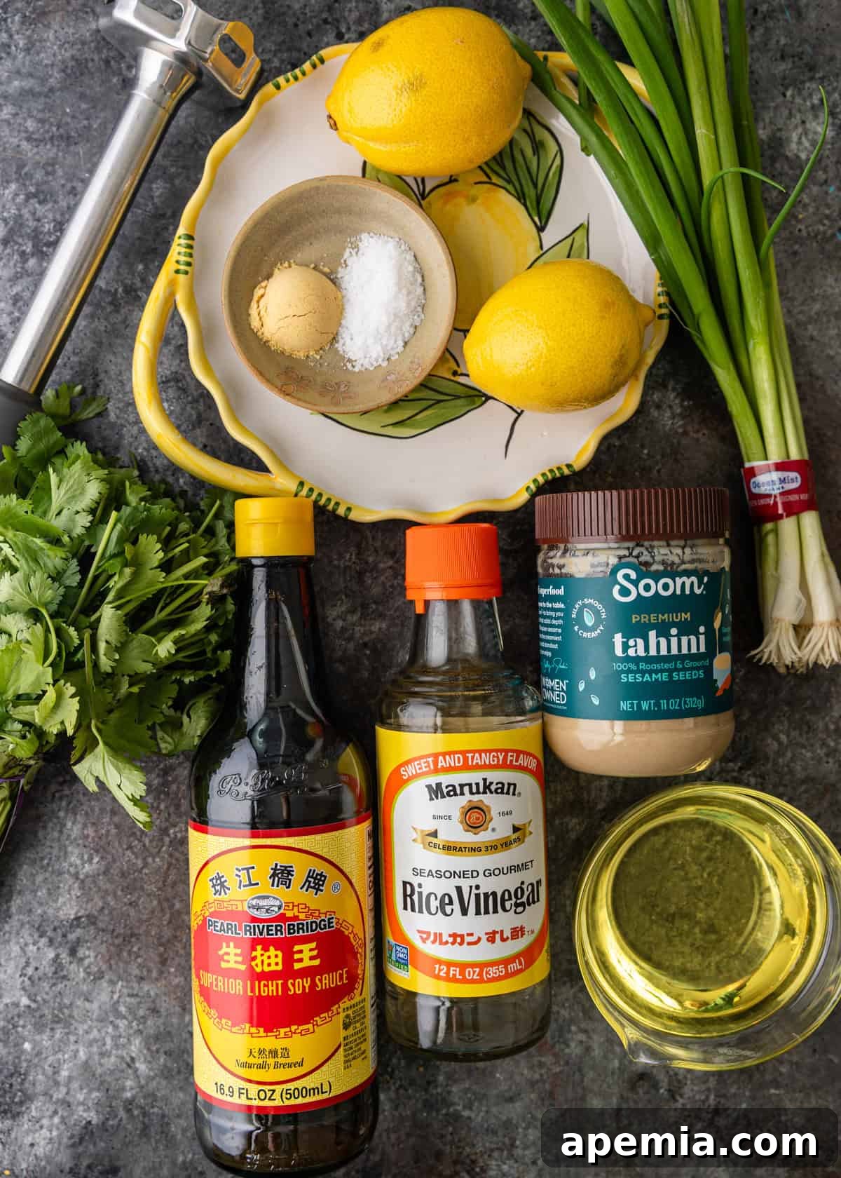 Overhead shot showcasing the fresh ingredients required to make the lemon tahini dressing recipe, including lemons, tahini, herbs, and spices, neatly arranged on a counter.