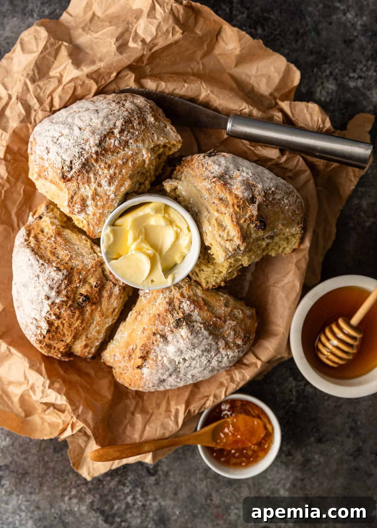 Overhead view of a freshly baked Irish soda bread in a basket, accompanied by a small dish of butter, ready to be served.
