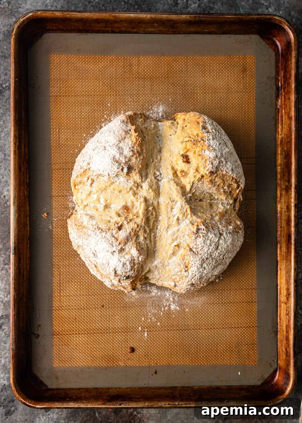 Overhead process shot showcasing the beautifully baked Irish soda bread loaf, golden brown and cooling on a baking sheet, fresh from the oven.
