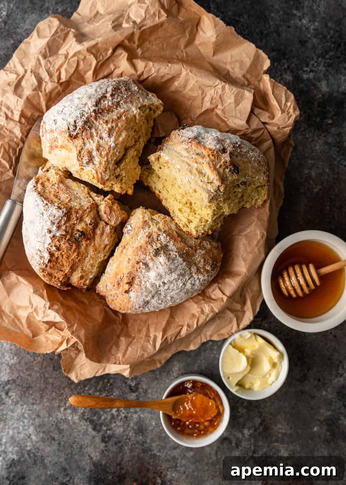 Overhead view of a beautiful Irish soda bread nestled in a basket, surrounded by various spreads like butter, jam, and honey.