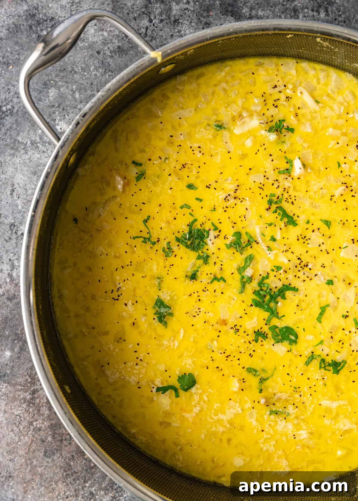 closeup overhead: ready to serve cod stew in pot topped with diced onions and pepper