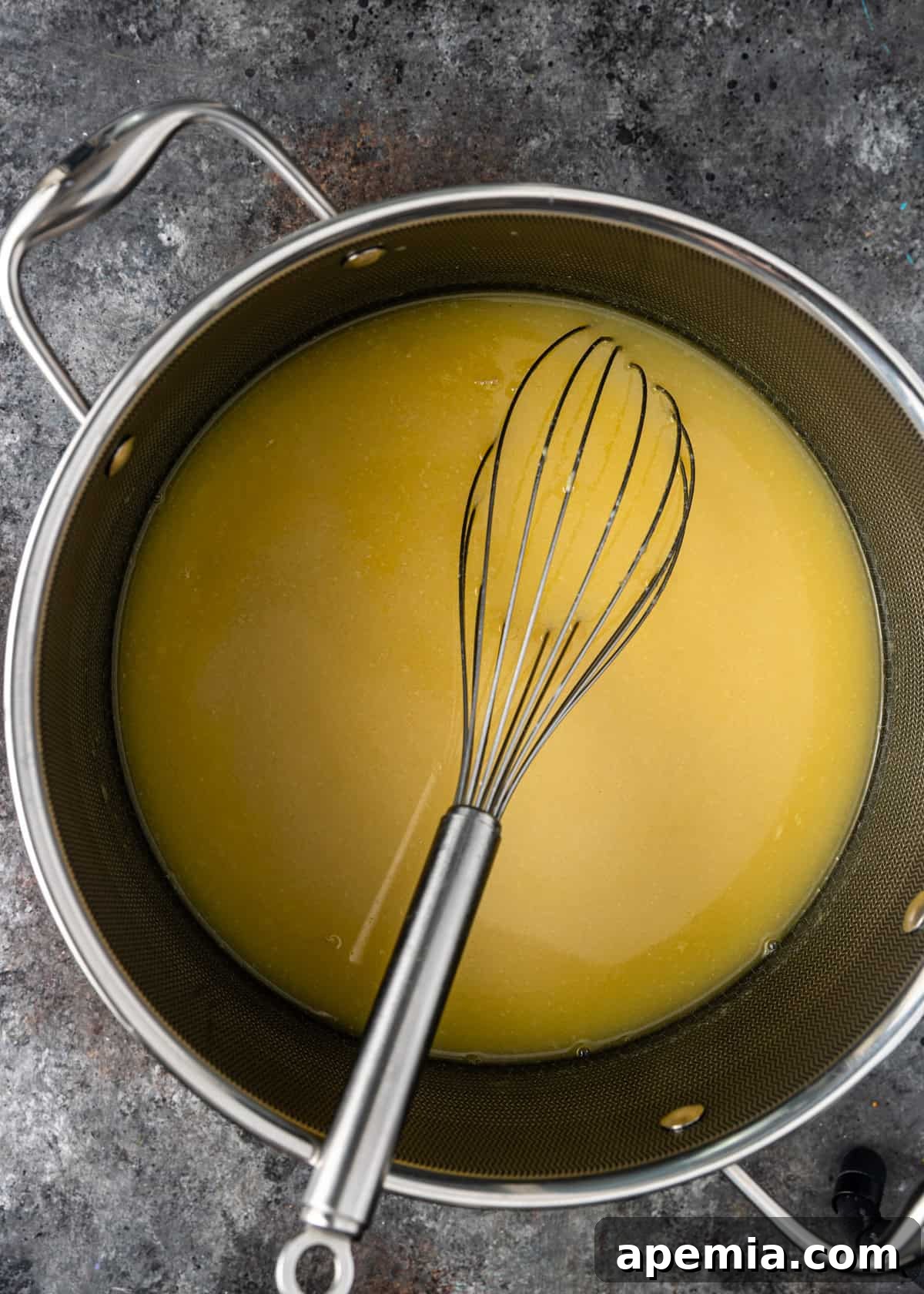 Process shot: whisking chicken stock as it comes to a boil in a large pot.