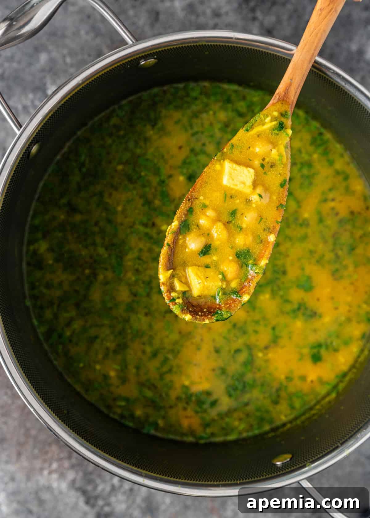 A spatula stirring the thickening semolina soup in a pot on the stove.