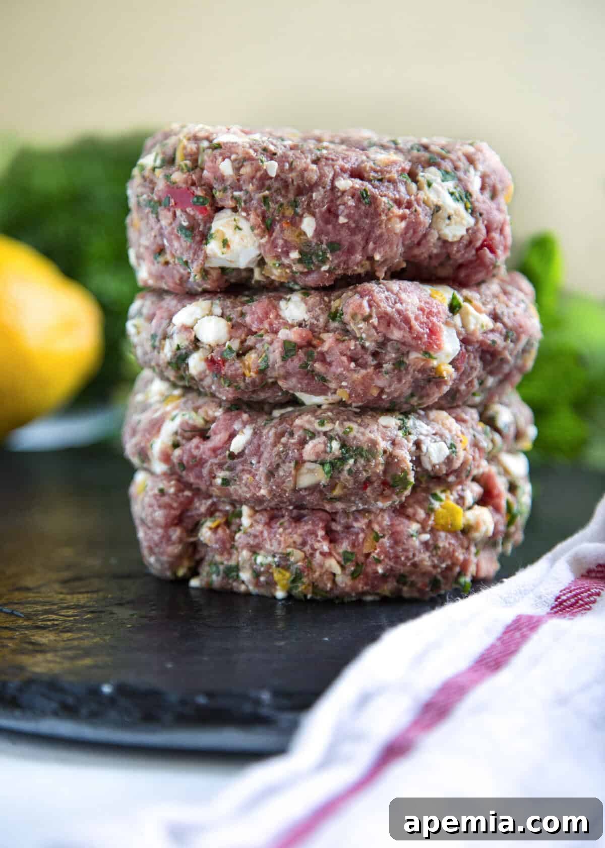 Grilled Greek Lamb Burger with Feta and Tzatziki 5 closeup side view: three lamb burger patties stacked on top of each other and ready to be cooked