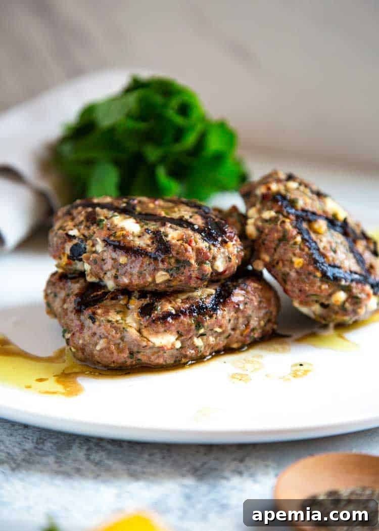 Grilled Greek Lamb Burger with Feta and Tzatziki 6 side view: three ready to eat Greek burgers on white plate