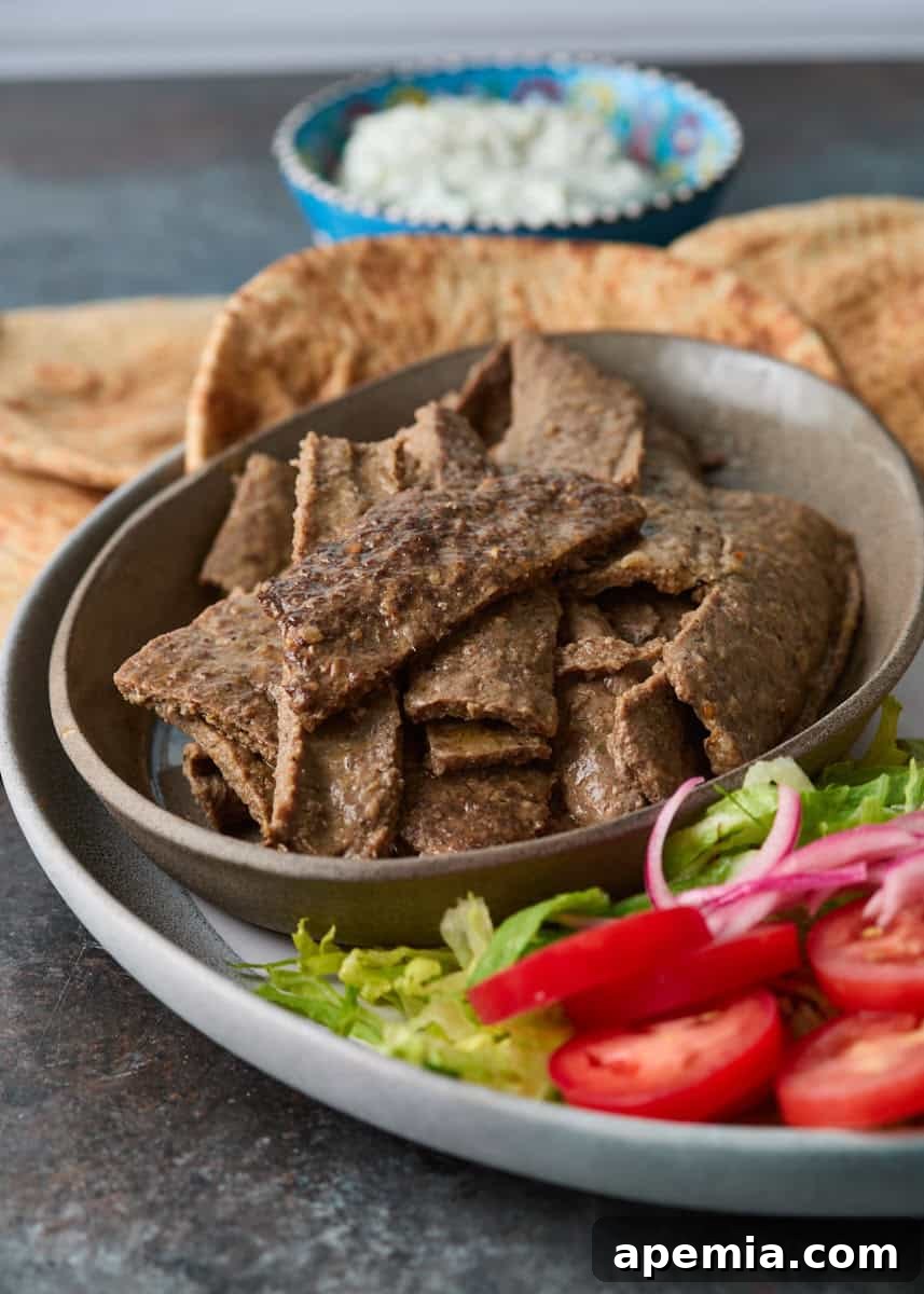 side view: bowl of sliced meat on top of plate with lettuce, onions, and tomatoes on side